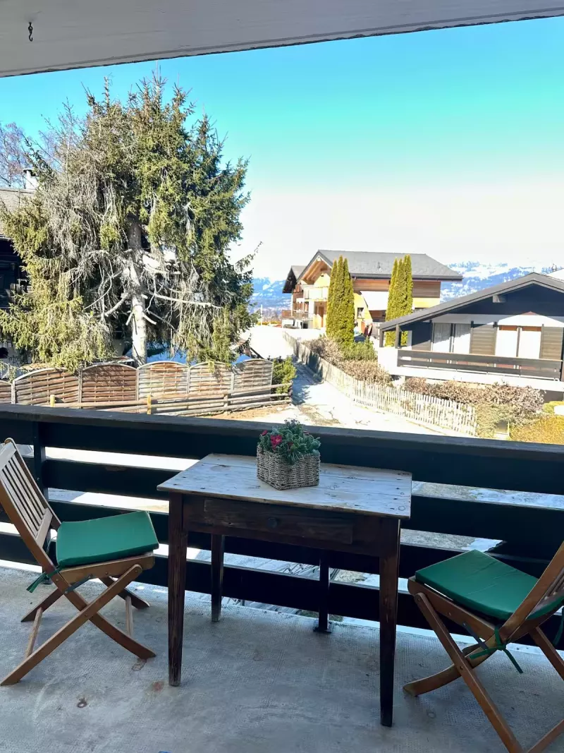 Balcon avec table, chaises et vue sur les chalets et les montagnes
