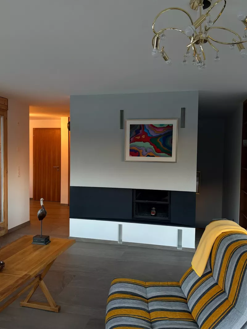 Salon avec cheminée et fauteuil rayé jaune et gris