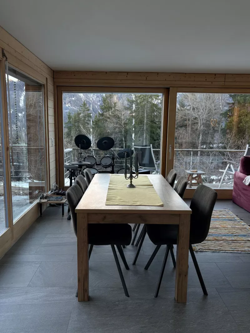 Table à manger devant les baies vitrées ouvertes sur la forêt