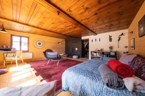 Chambre sous le toit d'un chalet avec couvre-lit bleu et coussins colorés