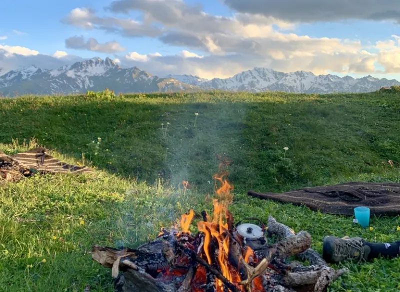 Feu de camp dans un pâturage face aux montagnes enneigées