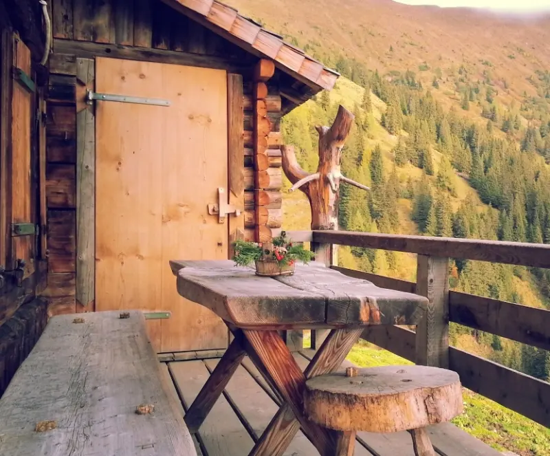 Entrée d'un mazot en bois avec banc, face à la forêt en automne